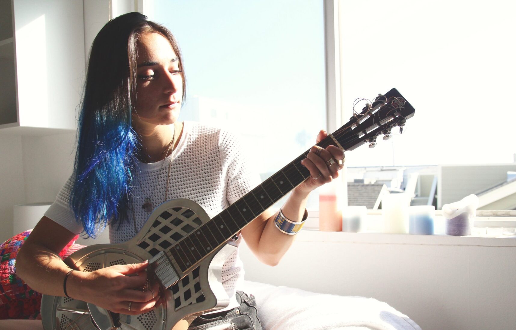   The sun shines on the side of Vane’s face as she peacefully practices her guitar chords.  
