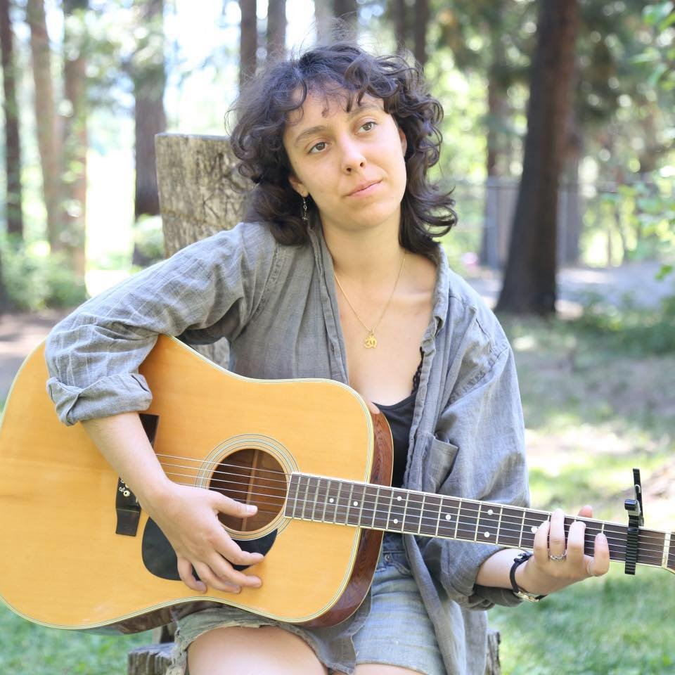   Leavy looks off contently into the distance, her fingers naturally clutching the strings of her acoustic guitar.  