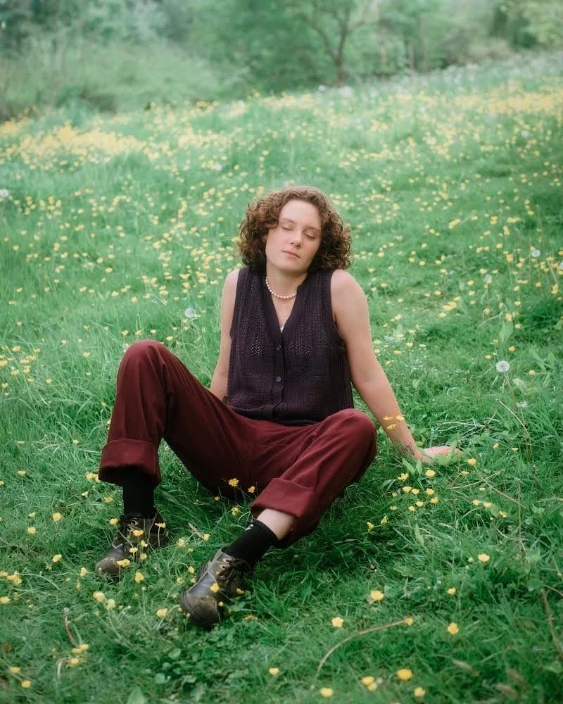   Simone sits peacefully in an open field, her closed eyes conveying the serenity of the scene. Photo courtesy of    Emily Gardner   