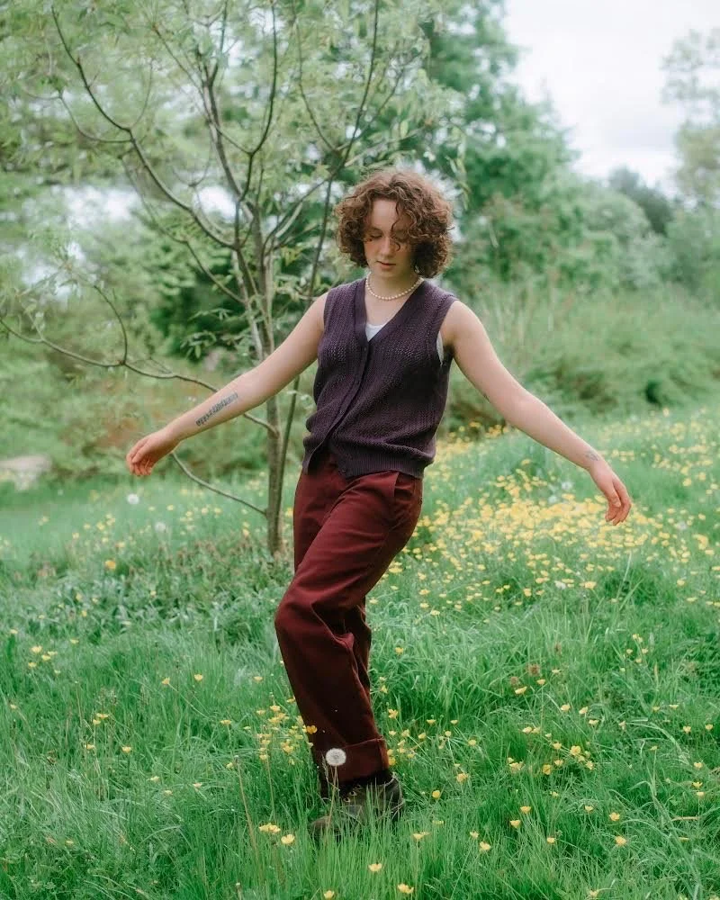   Simone frolicks gracefully in a field of dandelions, her dark clothing standing out amongst the blooming yellow flowers and other greenery. Photo courtesy of    Emily Gardner   