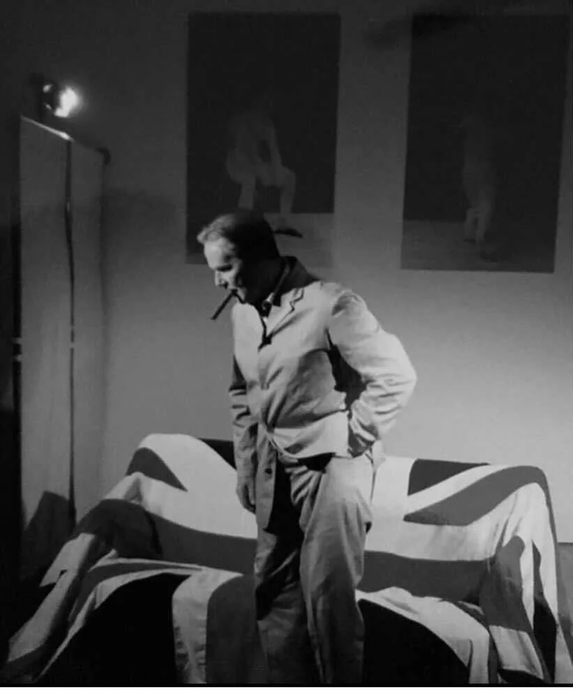 John Rowley (Frankie’s grandfather) stands in front of a couch covered by the Union Jack while smoking a cigar.